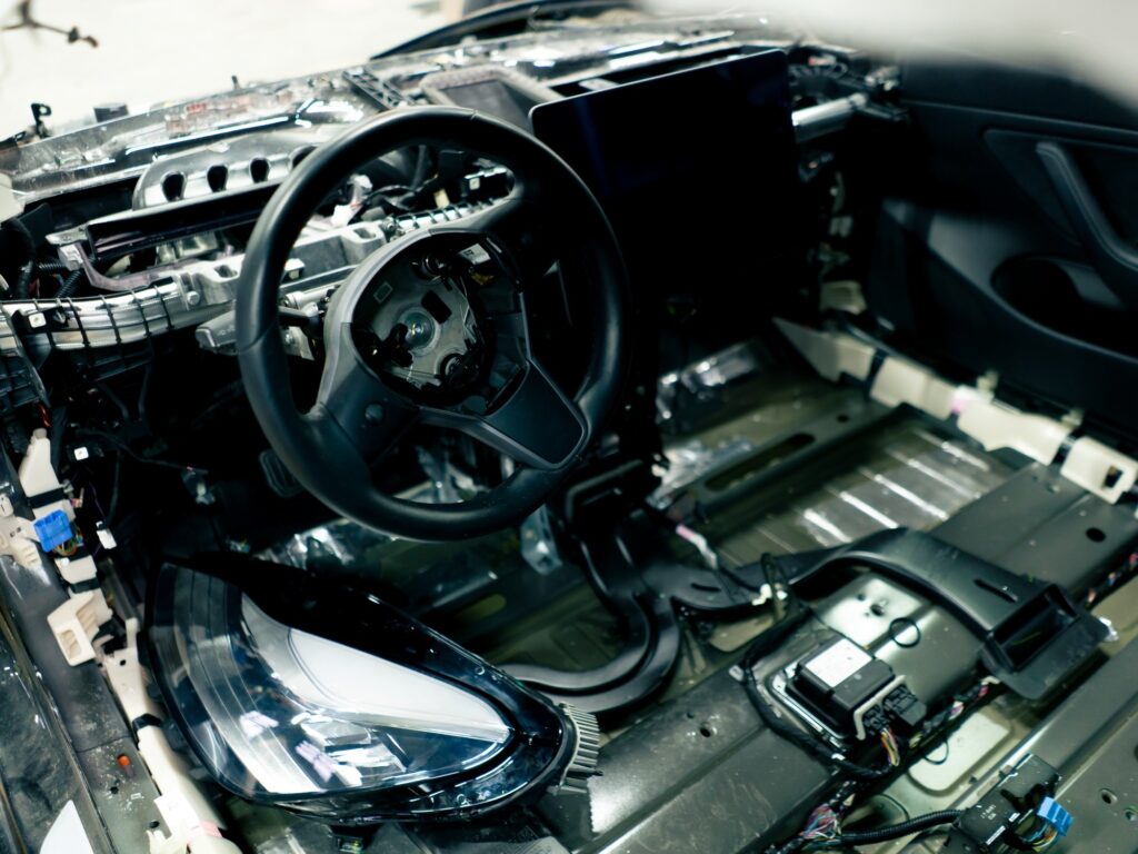 Interior de vehículo en línea de ensamble con tablero, volante y arnés eléctrico expuestos antes del montaje final