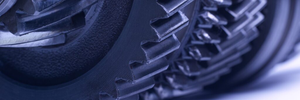 Detalle macro del engranaje helicoidal de una transmisión automotriz, dientes acoplados a la vista, tratamiento de marca en tono azul